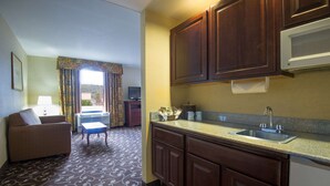 A compact hotel room with a kitchenette, a sofa, a small table, and a window with curtains. - Hampton Inn Brattleboro (Brattleboro)