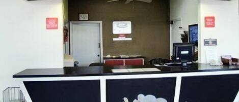 A reception desk with a black and white color scheme, a small television, and a sign above the door.