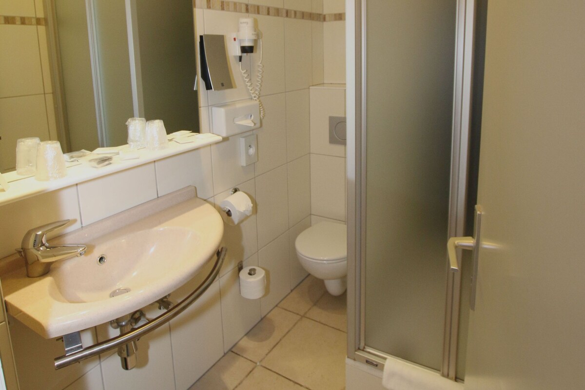 Un baño con lavabo, espejo, inodoro y cabina de ducha con paredes de vidrio.