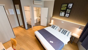 A hotel room with a bed, bedside table, and a wall-mounted TV. - Hôtel de l'Univers Liège (Liege)