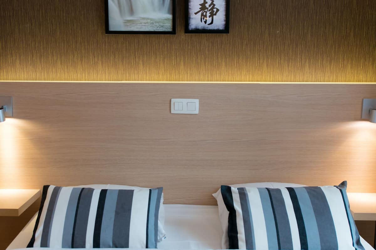 Une chambre d’hôtel avec une tête de lit en bois, un lit agrémenté d’oreillers à rayures et des tableaux encadrés accrochés au mur.