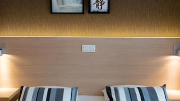 Een hotelkamer met een houten hoofdeinde, een bed met gestreepte kussens en ingelijste foto's aan de muur.