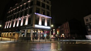 A hotel with a classic architectural style, featuring a prominent marquee sign and a well-lit entrance. - Hôtel de l'Univers Liège (Liege)