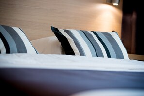 A neatly made bed with striped pillows and a wooden headboard.