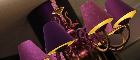 Ein Kronleuchter mit violetten Schirmchen und goldenen Verzierungen.