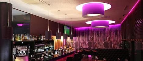 A bar area with a counter, bar stools, and a seating area with tables and chairs.