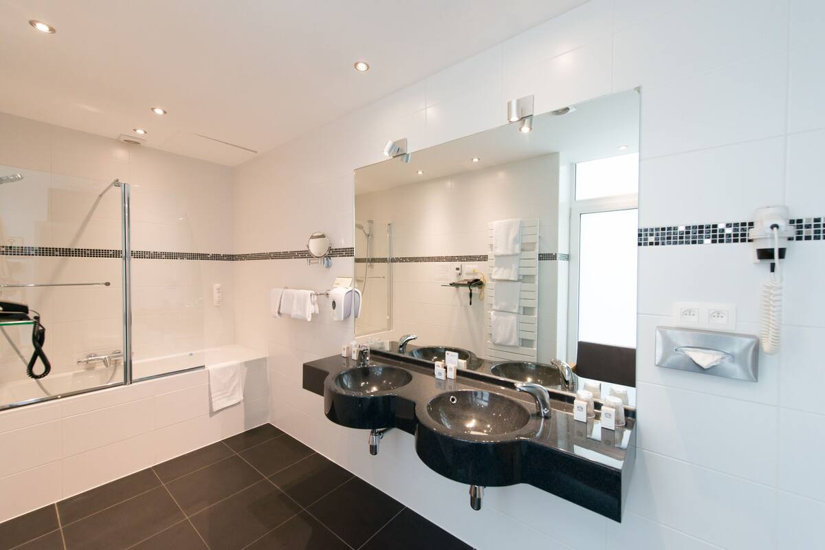 Une salle de bain moderne avec deux lavabos, une douche à parois de verre et un grand miroir.