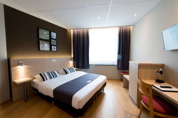 A modern hotel room with a bed, bedside table, desk, and a window with curtains. - Hôtel de l'Univers Liège (Liege)
