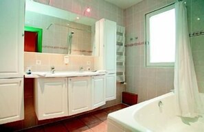 A bathroom with a bathtub, a large mirror, and a window. - Hôtel de l'Univers Liège (Liege)