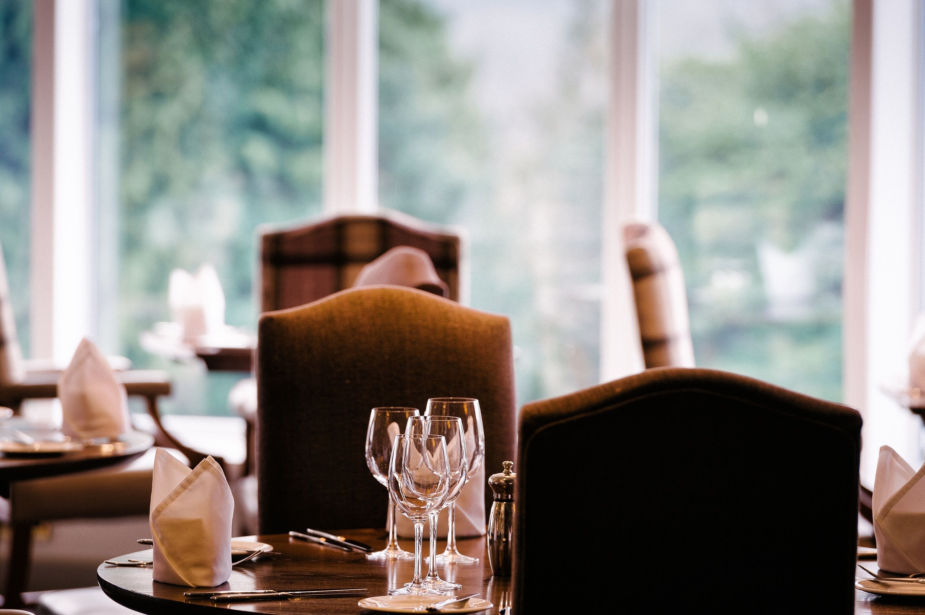 Une table à manger dressée avec des verres à vin, un salier et des serviettes pliées.