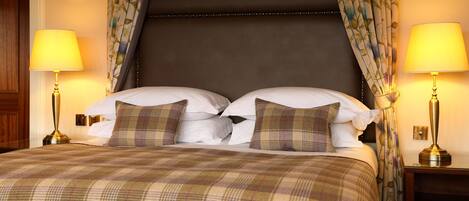 Una habitación de hotel con una cama grande, dos lámparas de noche y cortinas estampadas.