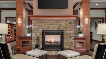 A lobby with a stone fireplace, seating area, and a television mounted on the wall.