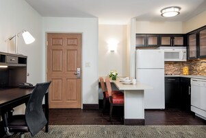 A compact kitchen with a dining area, a wooden door, and a modern light fixture.