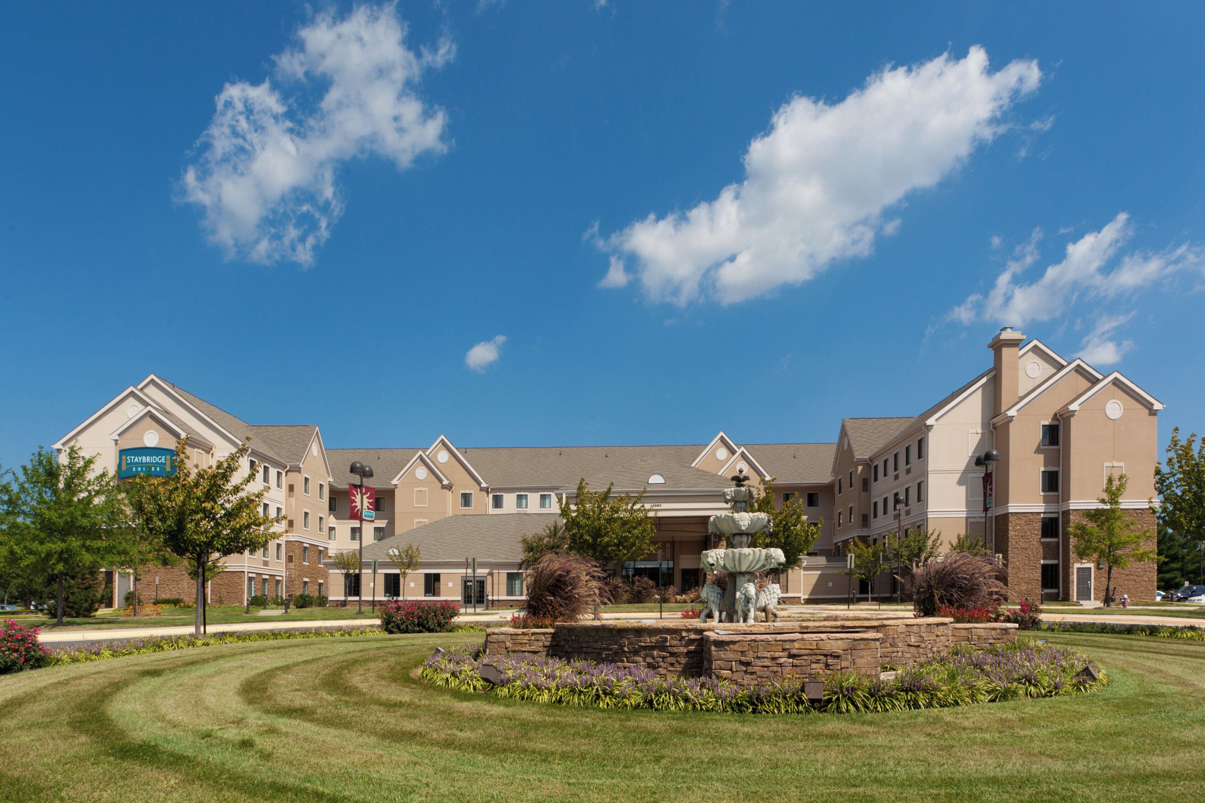 Un hotel con un patio central, una fuente y un letrero de Staybridge Suites.