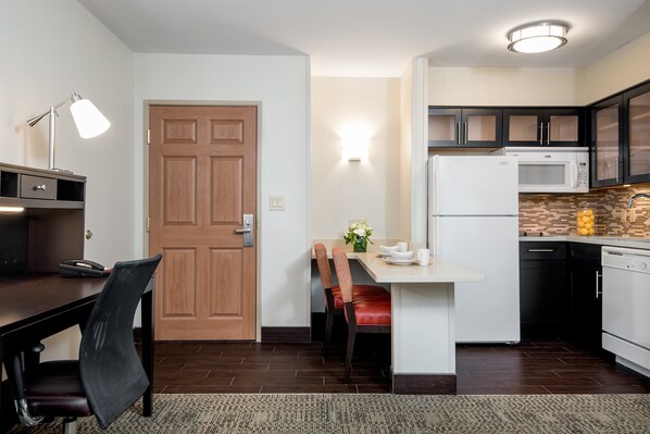 A compact kitchen with a dining area, a wooden door, and modern appliances.