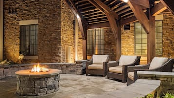 An outdoor patio with stone walls, a fire pit, and wicker furniture.