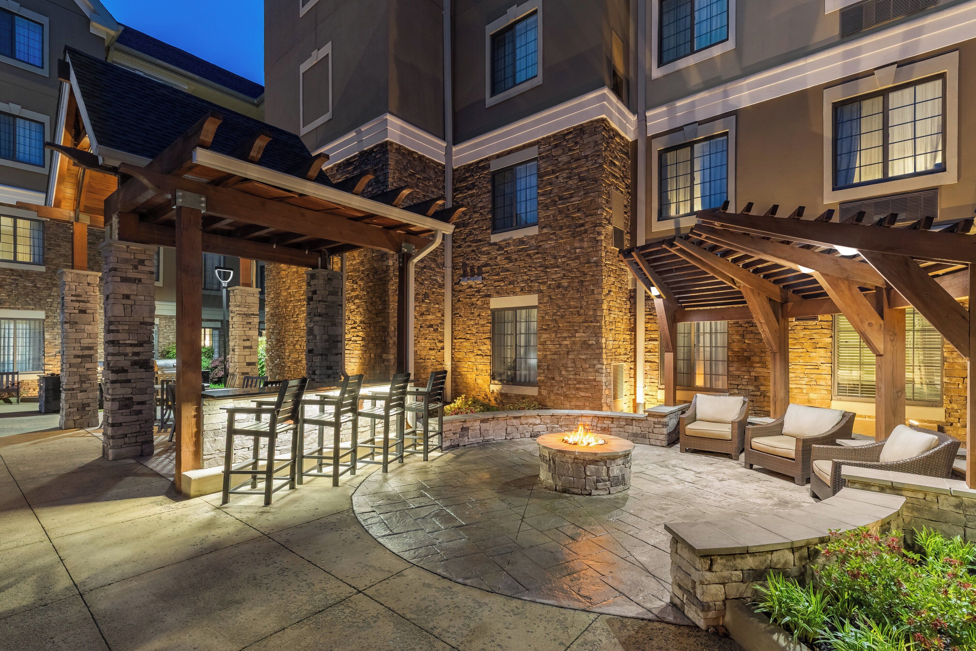 An outdoor patio area with stone pillars, a fire pit, and outdoor seating.