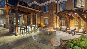 An outdoor patio area with stone pillars, a fire pit, and outdoor seating.