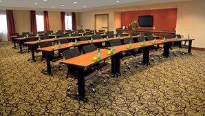 A conference room with multiple tables, chairs, and a television screen on the wall.
