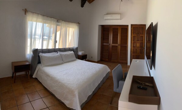 Un dormitorio con cama, escritorio, silla, televisor y armario.