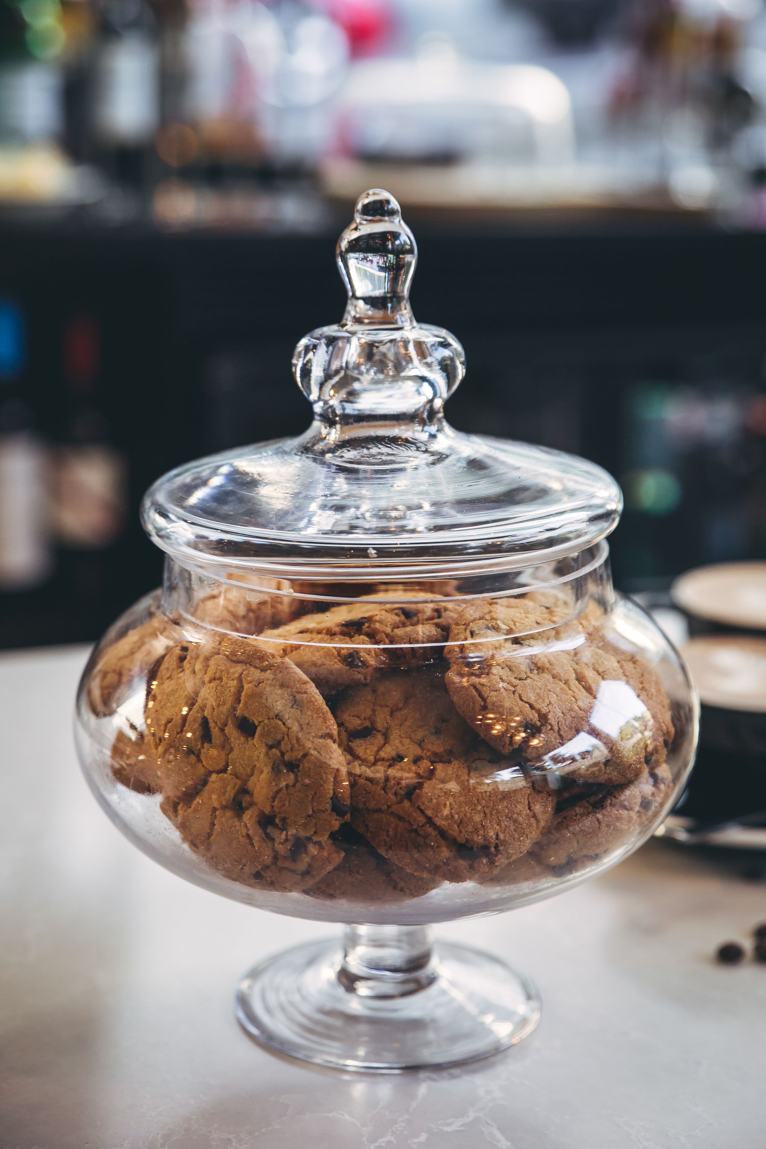 A glass jar filled with cookies on a table.
