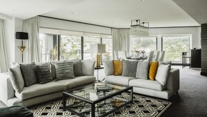 Uma sala de estar moderna com um sofá, uma mesa de centro de vidro e um tapete estampado.