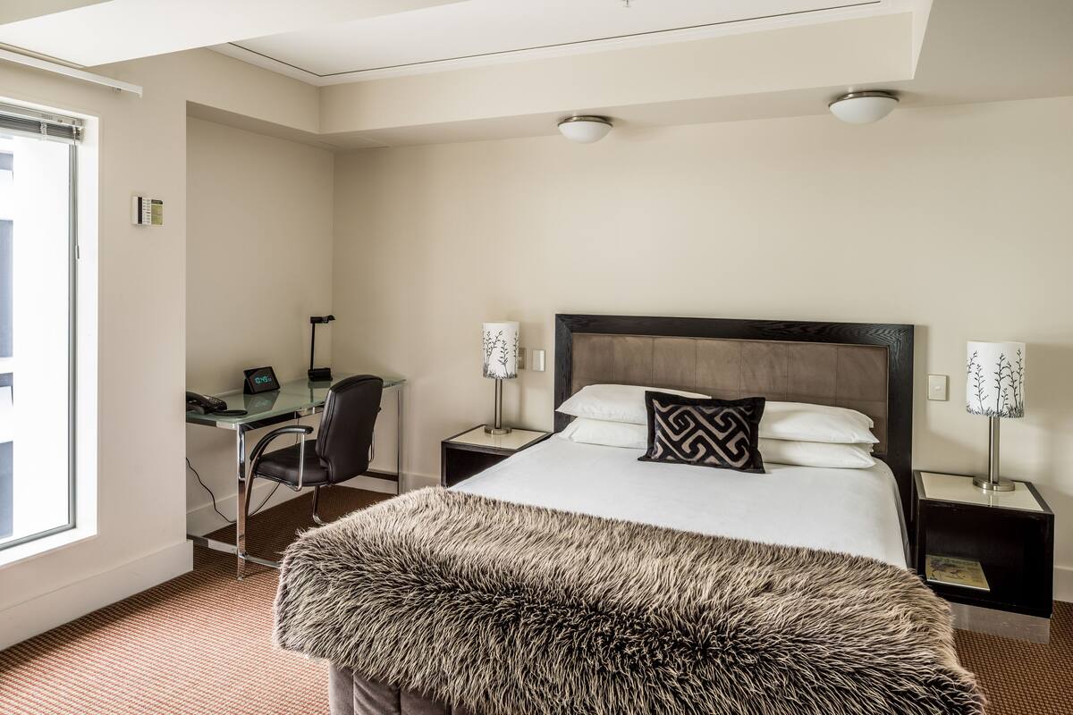 Ein Hotelzimmer mit Bett, Schreibtisch und Stuhl.