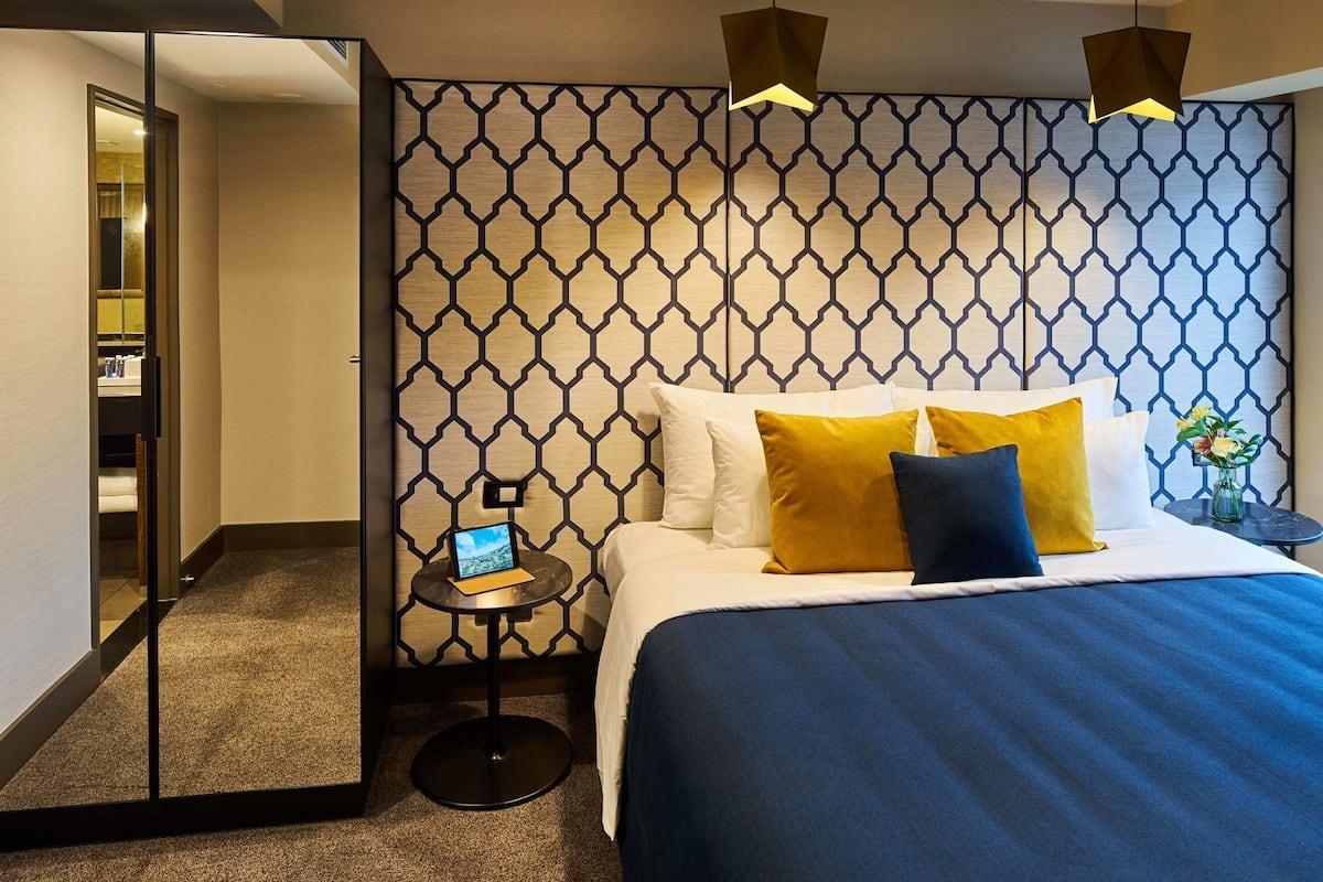 Ein Hotelzimmer mit einem Bett, einem kleinen Tisch mit einem Laptop und einem Spiegel.