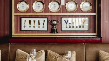 L’intérieur d’un restaurant présente une table en bois dressée pour le repas, un banc rembourré et un mur où sont exposés, encadrés, des prix et des médailles.