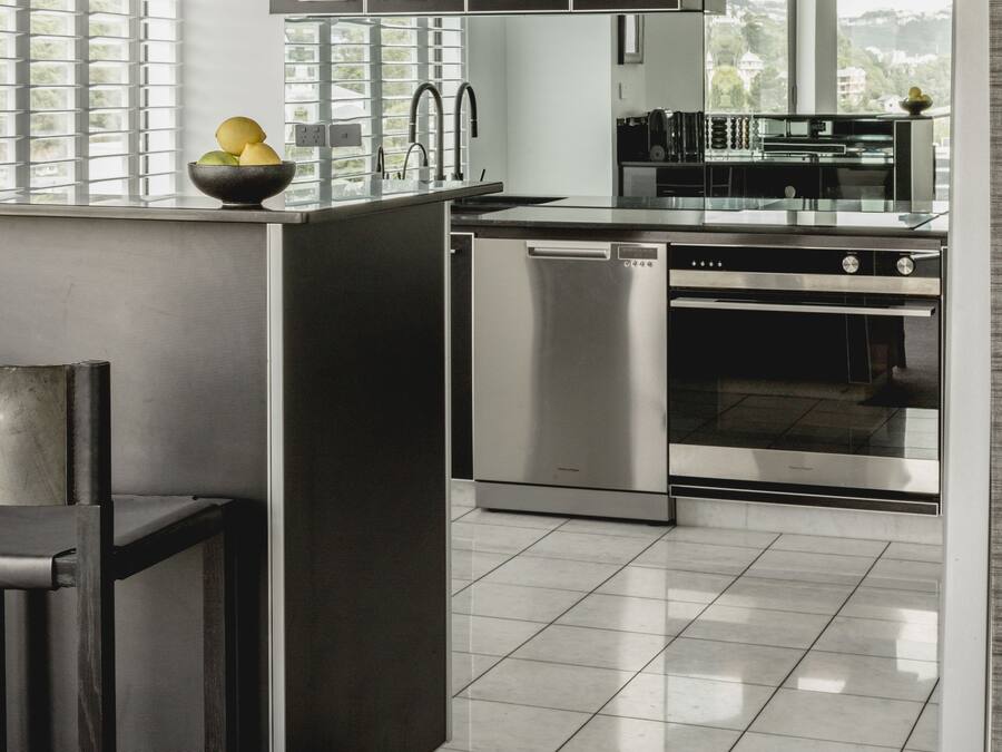 A modern kitchen with a central island, stainless steel appliances, and a view of the outdoors.