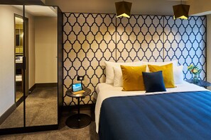 A hotel room with a bed, a nightstand, a mirror, and a geometric-patterned wall. - Bolton Hotel (Wellington)