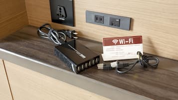 Una camera d'albergo con un bancone in legno, un router nero, un segnale Wi-Fi e una presa di corrente.