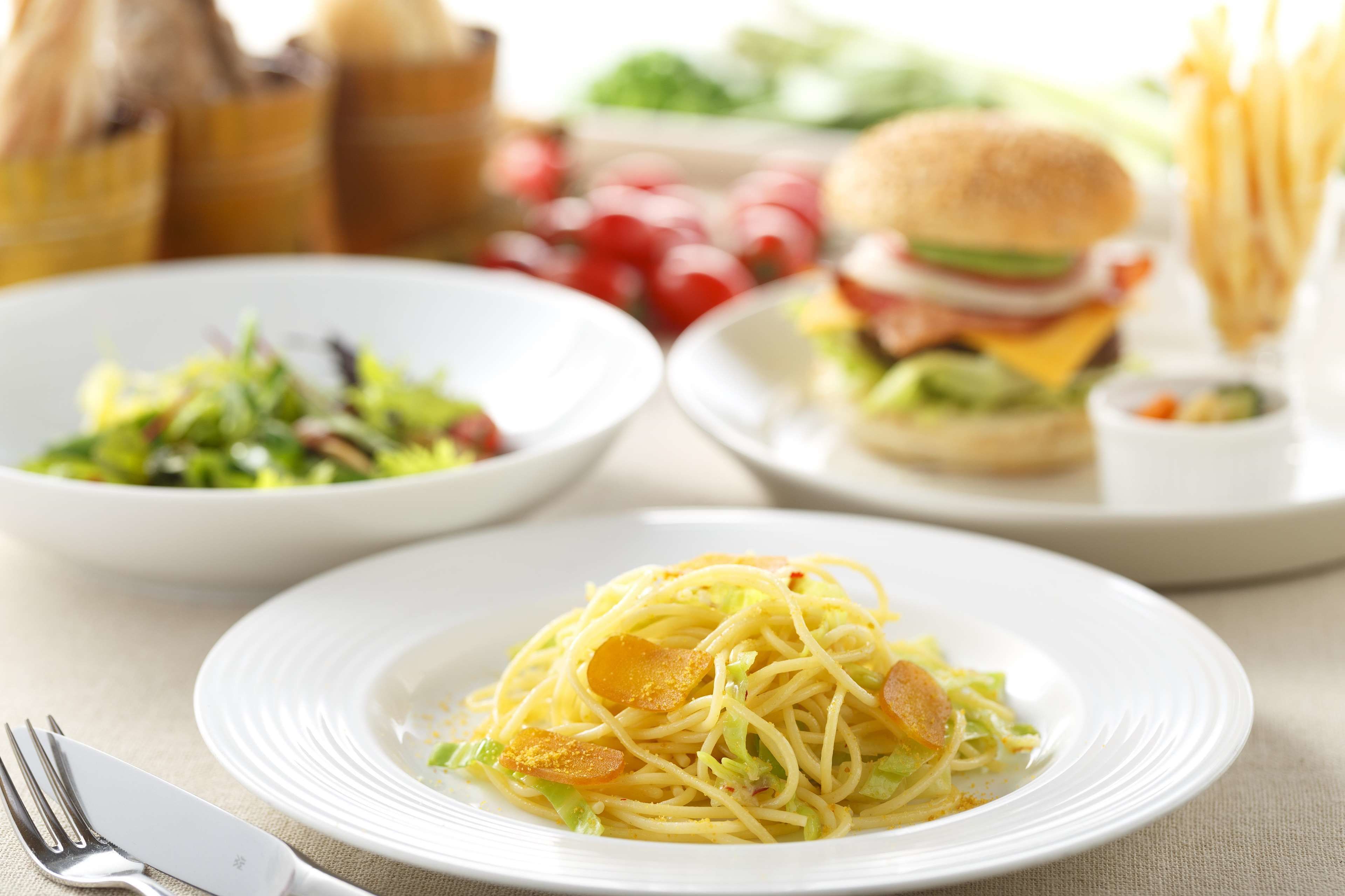 A plate of spaghetti with meatballs and a side salad.