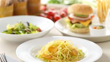 A plate of spaghetti with meatballs and a side salad.