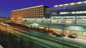 A modern building with a sign reading "Terminal 2" and multiple levels with illuminated windows.