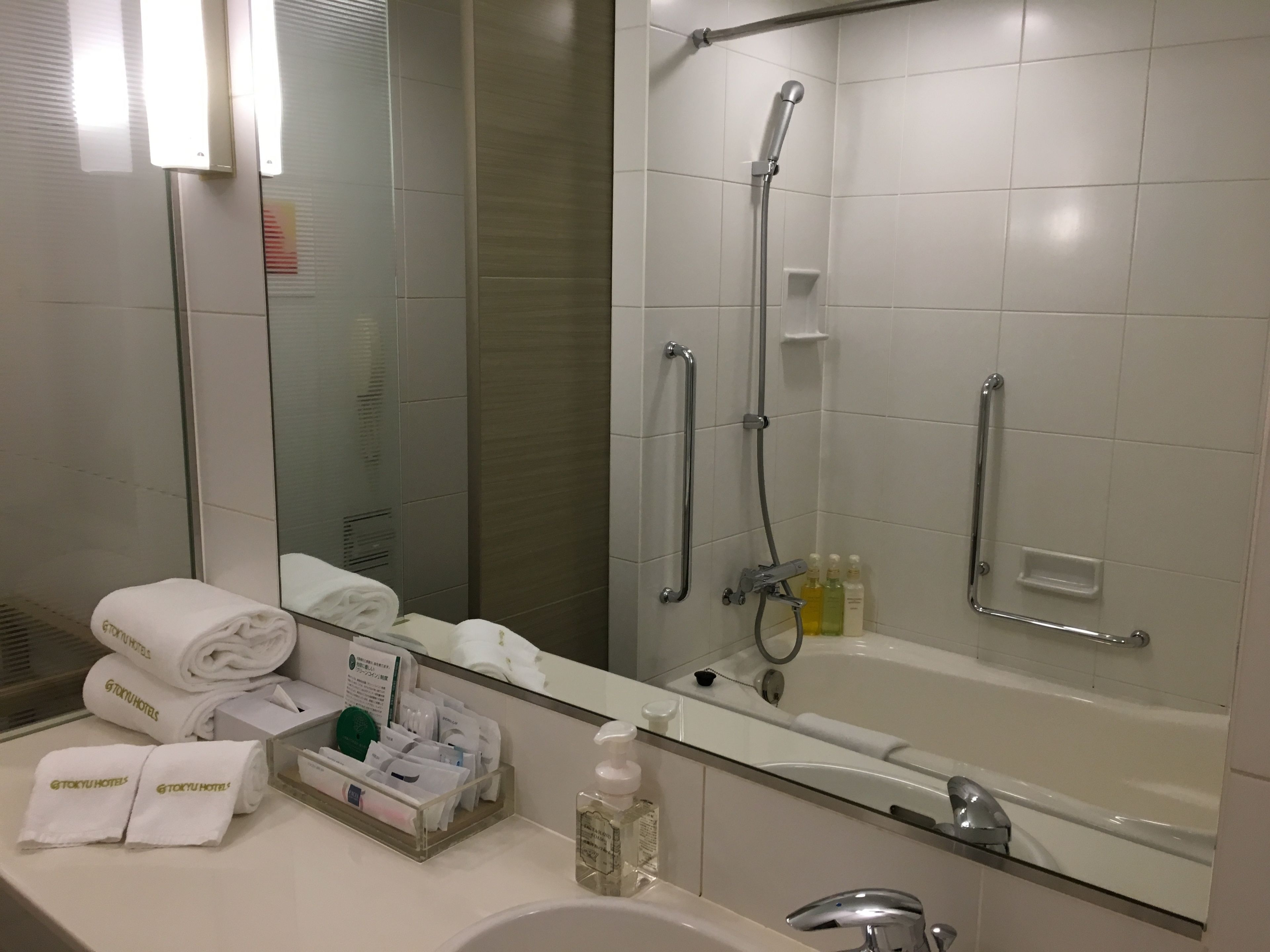 Moderni kylpyhuone, jossa on kylpyamme, suihku, suuri peili ja allaskaappi, jossa on hygieniatuotteita.