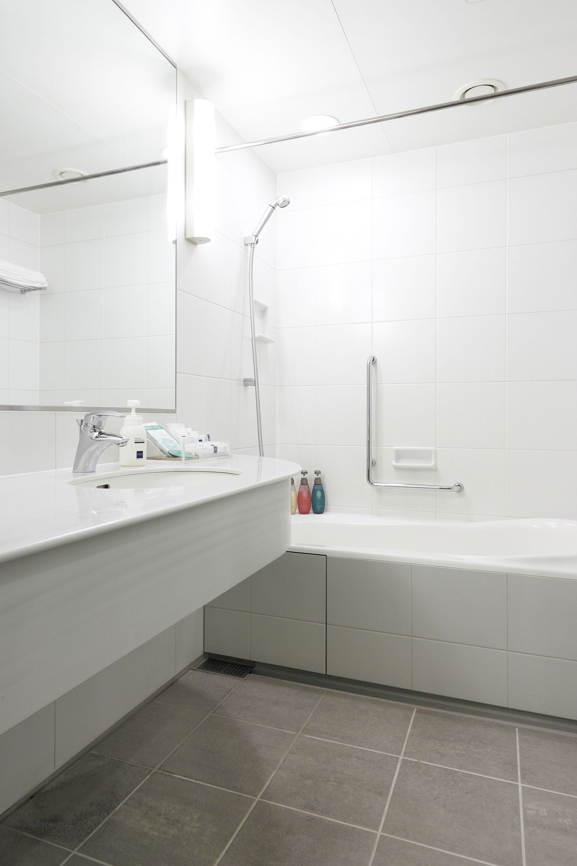 A modern bathroom with a white sink, mirror, and bathtub.