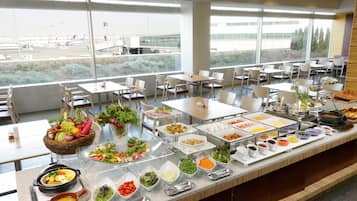 A buffet with various food options and a view of an airport in the background.