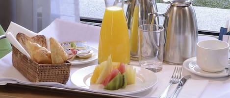 A breakfast tray with croissants, fruit, juice, and coffee.