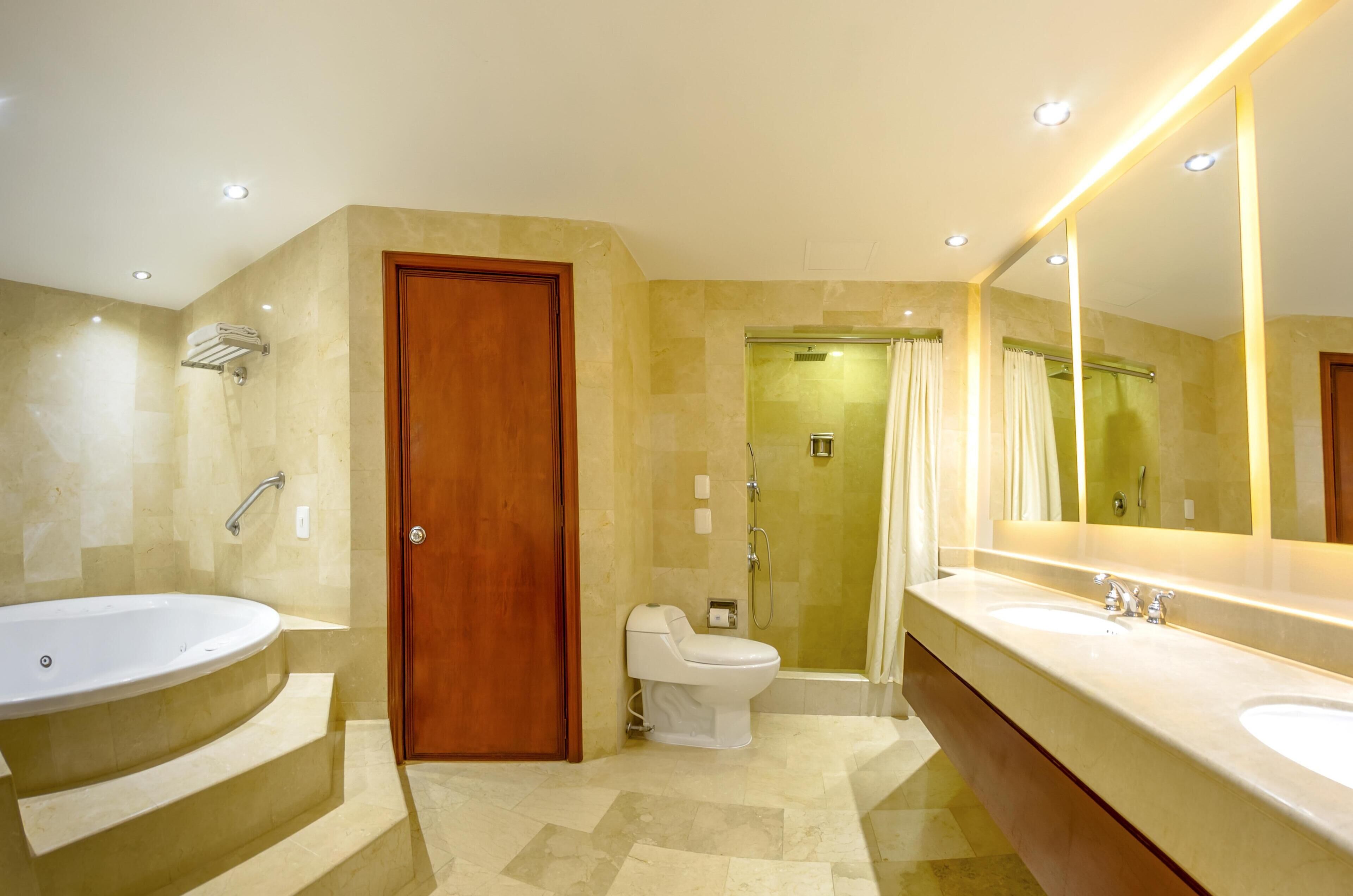 A bathroom with a bathtub, a toilet, a shower, and a large mirror.