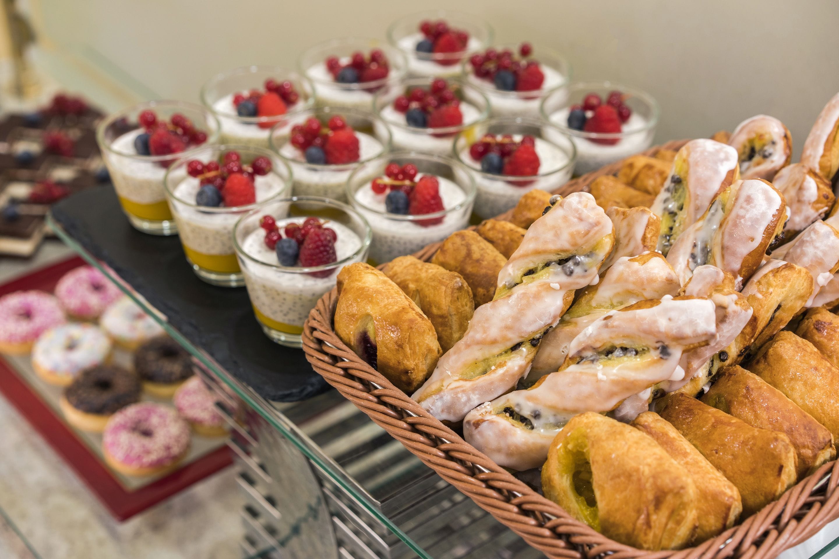 A buffet with various desserts including pastries, fruit tarts, and small glass desserts topped with berries.