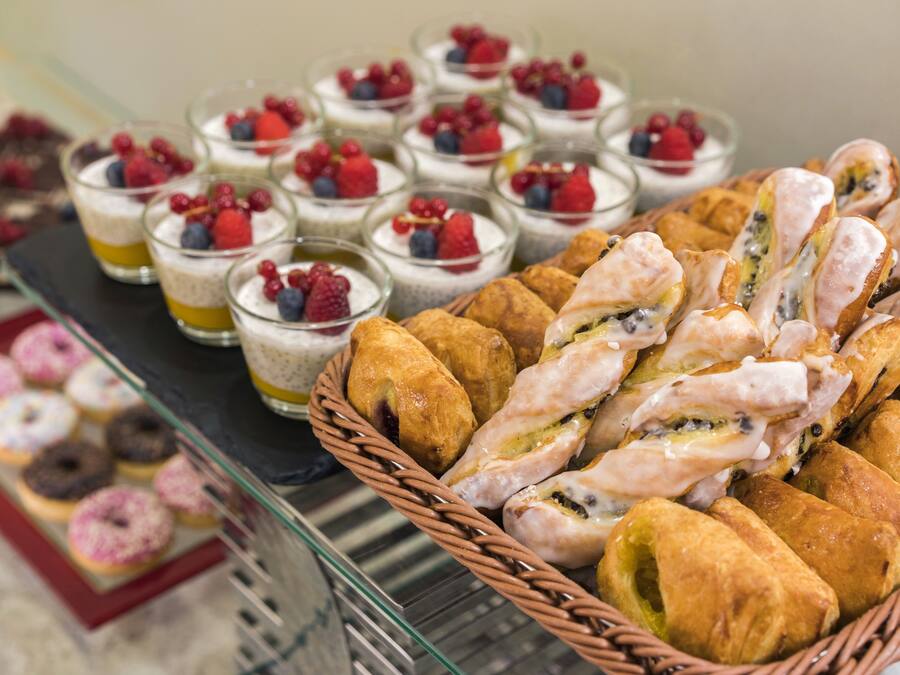 A buffet with various desserts including pastries, fruit tarts, and small glass desserts topped with berries.