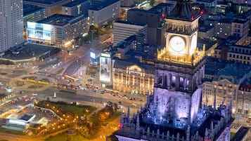 A historic building with a prominent clock tower, surrounded by modern high-rise buildings and busy streets.