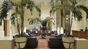 A lobby with a central seating area, palm trees, and a reception desk. - Polonia Palace Hotel (Warsaw)