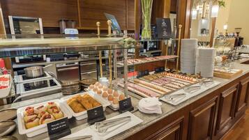 A buffet with various food items, including pastries, eggs, and meats.