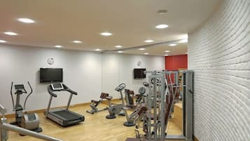 Un gimnasio con cintas de correr, elípticas y equipo de pesas.