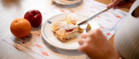 A plate with pastries and fruits on a table with a placemat.