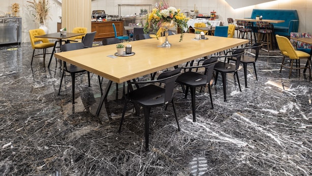 A modern dining area with a marble floor, a long wooden table, and yellow chairs. - Hotel El Greco (Thessaloniki)