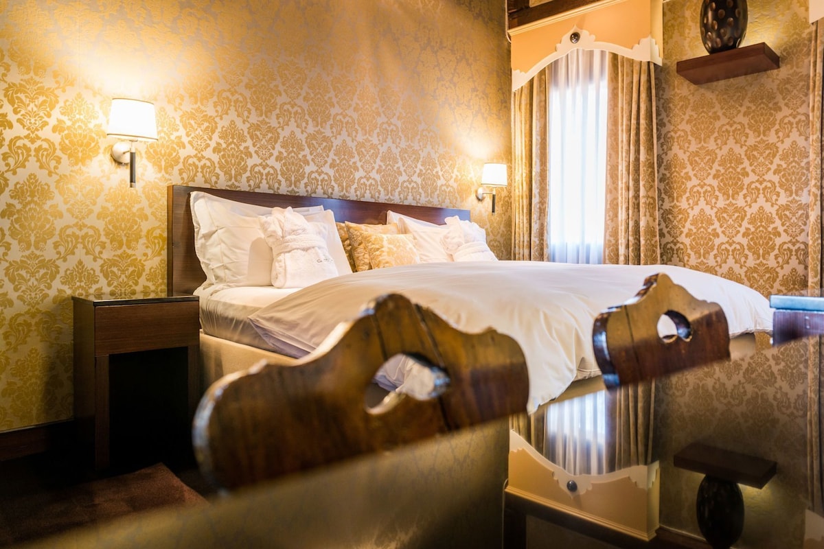 Een hotelkamer met een bed, nachtkastjes en wandlampen.