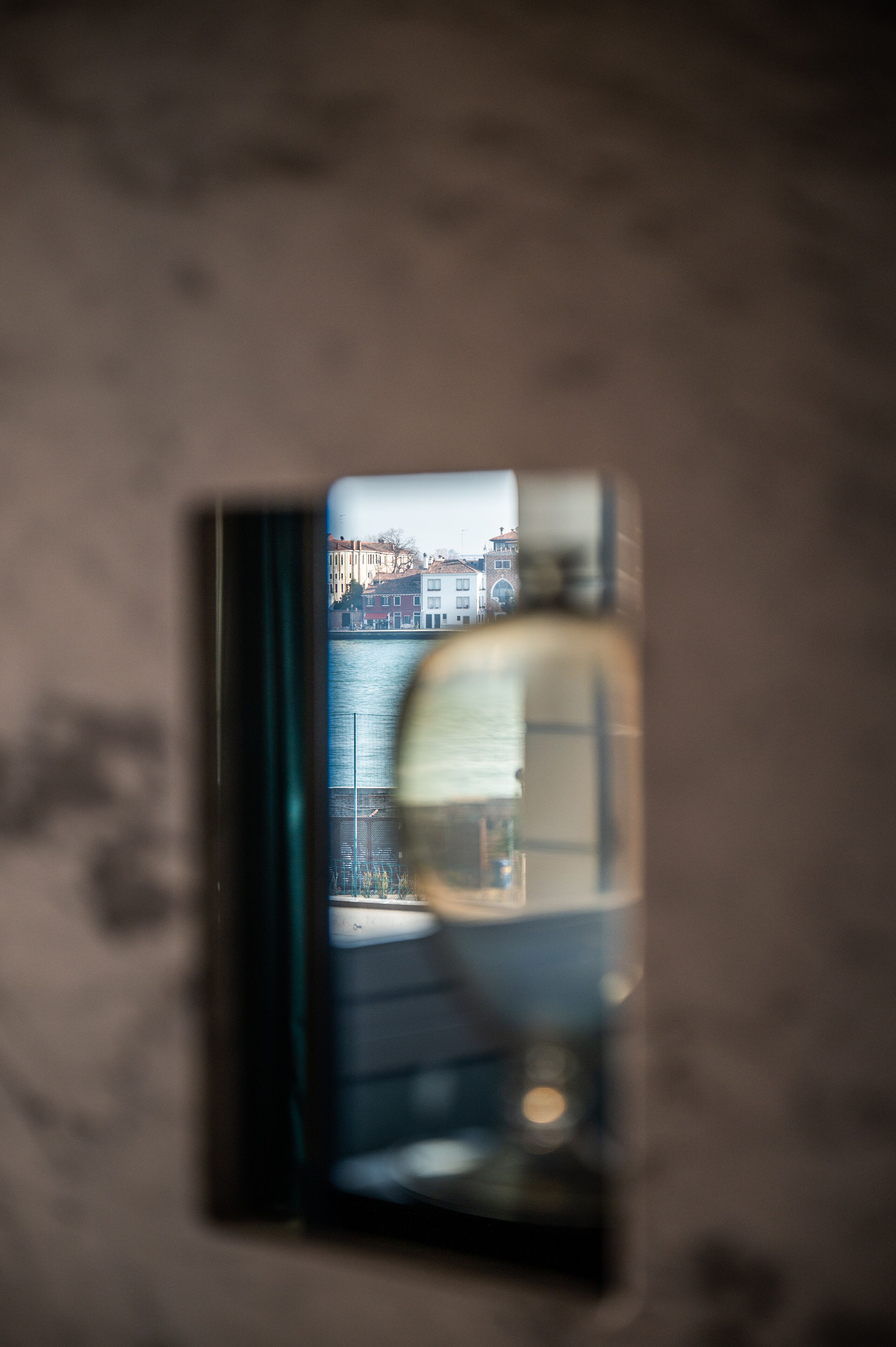 A view through a window with a reflection of buildings and a body of water.